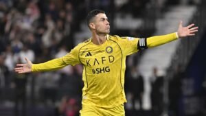 Cristiano Ronaldo celebrating in Al Nassr's yellow kit with arms outstretched, showcasing his confidence during a match.