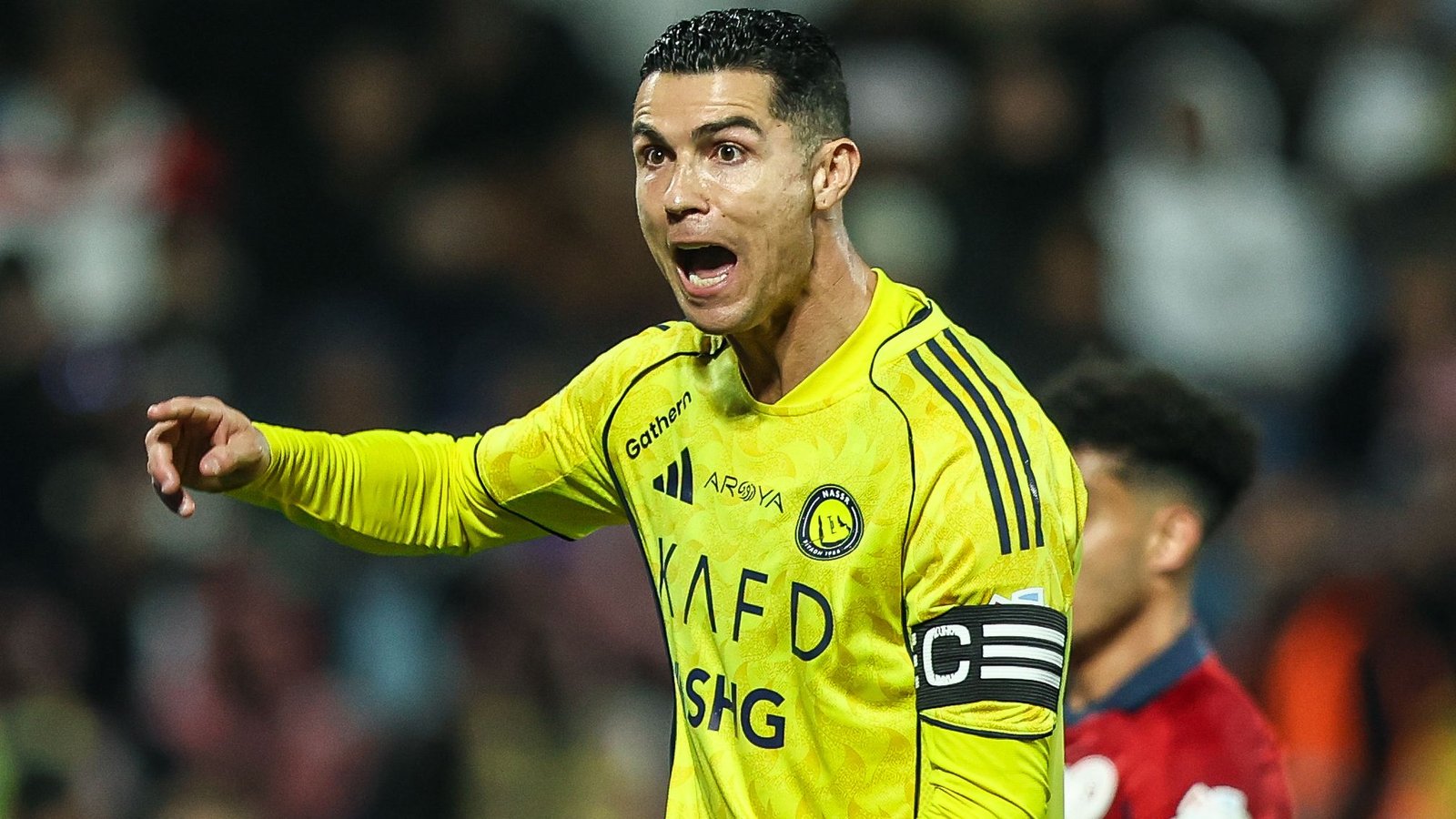 Cristiano Ronaldo en tenue jaune d'Al Nassr, gesticulant avec passion lors d'un match contre Al Ittihad, démontrant son leadership sur le terrain.