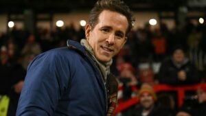 Ryan Reynolds sourit lors d'un match de Sheffield Wednesday, entouré de supporters enthousiastes dans le stade.