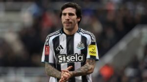 Sandro Tonali in Newcastle United's black and white kit, clapping in appreciation towards fans during a match.