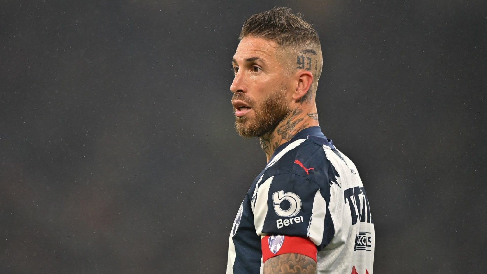 Sergio Ramos in Monterrey's blue and white kit, looking determined with a captain's armband and notable tattoo on his head.