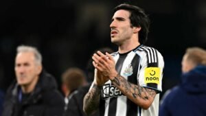 Sandro Tonali in a Newcastle United kit, applauding the fans, wearing the captain's armband in a stadium setting.
