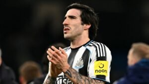 Sandro Tonali, vêtu du maillot de Newcastle United arborant un logo sponsor jaune, joint les mains en signe de réflexion sur le terrain.