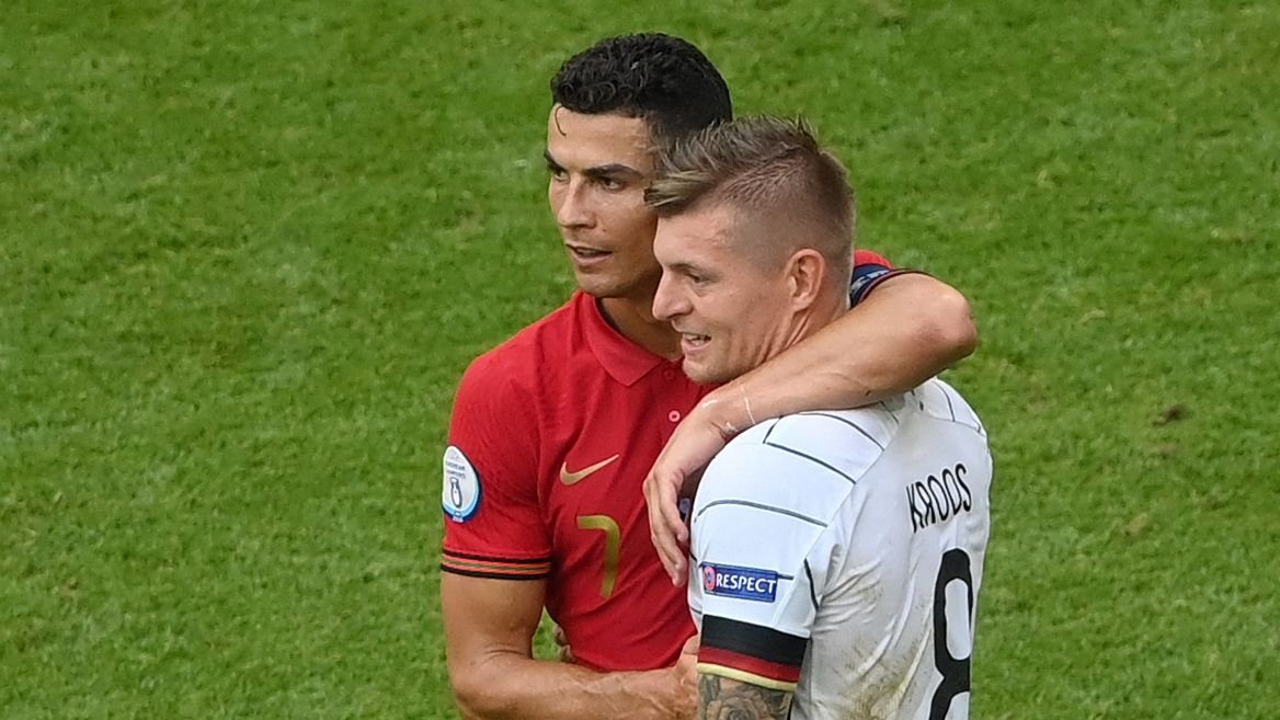 Cristiano Ronaldo in Portugal kit embraces Toni Kroos in Germany kit during a match, showcasing sportsmanship at Euro 2020.