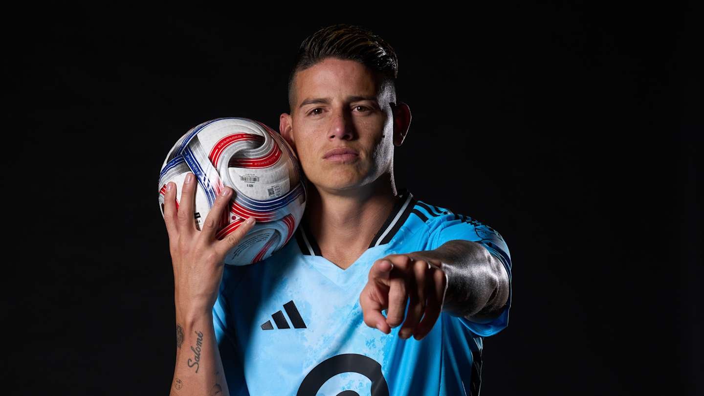 James Rodríguez poses in a turquoise goalkeeper kit, holding a patterned football and pointing directly at the viewer.