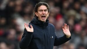 Thomas Frank, l'entraîneur de Brentford, gesticulant avec animation en bord de terrain, vêtu d'un manteau marine, durant un moment tendu d'un match.