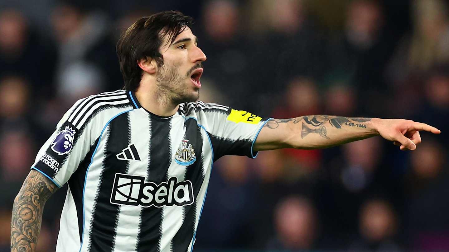 Newcastle United player wearing a black and white striped jersey, gesturing passionately during a match, showcasing team spirit and determination.