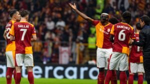 Victor Osimhen gestures to his Galatasaray teammates after their victory over Juventus, amidst a vibrant stadium atmosphere.