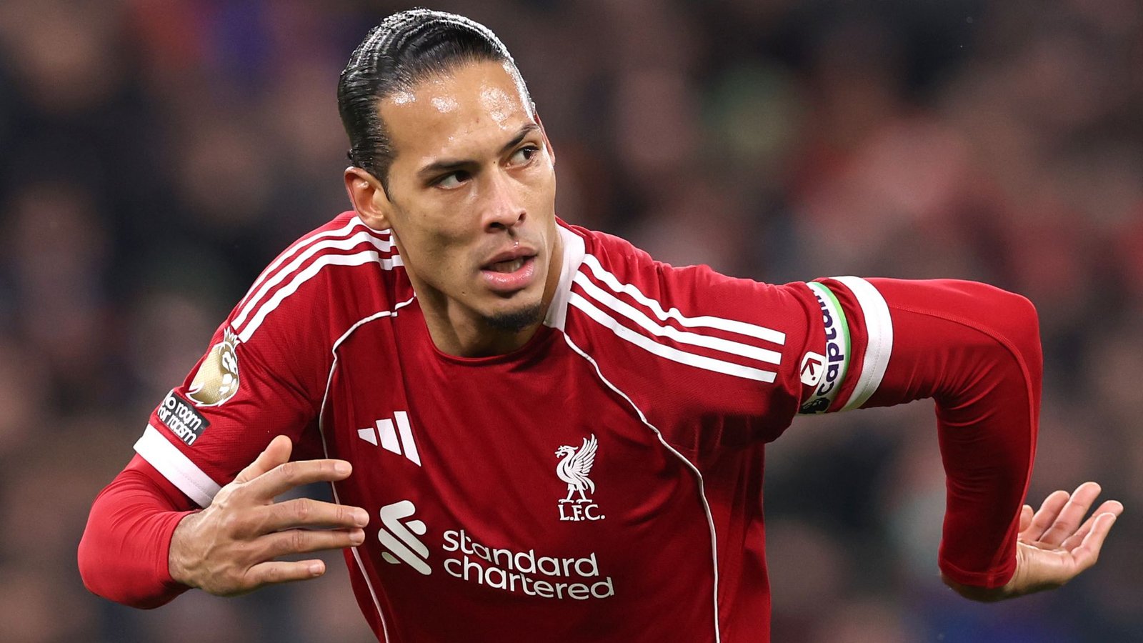 Virgil van Dijk portant le maillot rouge de Liverpool, célébrant un but avec détermination, arborant son brassard de capitaine sur le terrain.