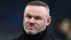 Wayne Rooney, gekleed in een donkere jas en met kort geknipt haar, heeft een ernstige uitdrukking, waarschijnlijk reflecterend op een recente wedstrijd.