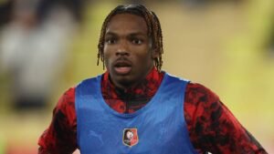 Jeremy Jacquet in a vibrant red and black training top, wearing a blue bib, looking focused during warm-ups.
