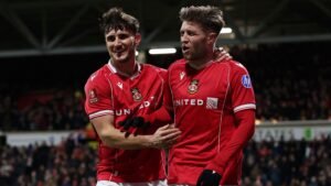 Wrexham-spelers vieren een doelpunt tijdens hun FA Cup-wedstrijd tegen Ipswich, waarbij teamgeest wordt getoond in hun rode tenues.