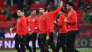 Moroccan national team players in red tracksuits greet fans before a match, showcasing team spirit and camaraderie.
