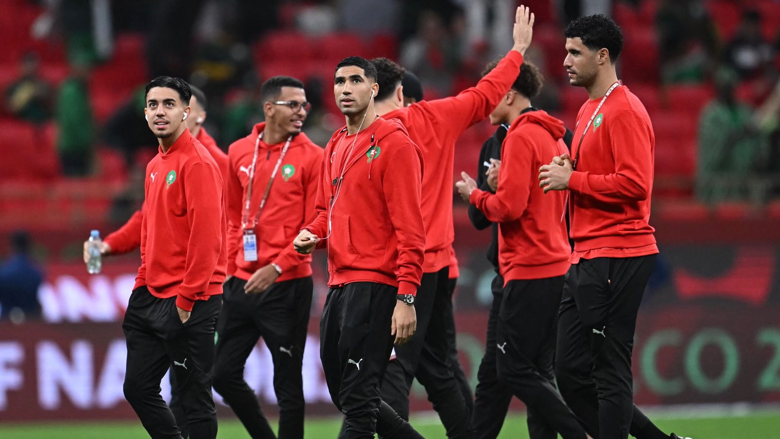 Moroccan national team players in red tracksuits greet fans before a match, showcasing team spirit and camaraderie.