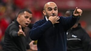 Walid Regragui gebaart gepassioneerd vanaf de zijlijn tijdens een wedstrijd, spoelt spelers aan terwijl een mede-coach op de achtergrond toekijkt.