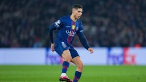 Achraf Hakimi, wearing the blue Paris Saint-Germain kit, dribbling the ball on the pitch during a match.