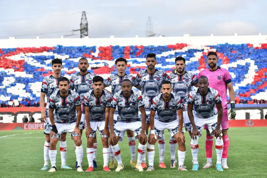 Moroccan football team lineup posing in front of a vibrant, colourful fan display, wearing unique, patterned jerseys for a cup match.