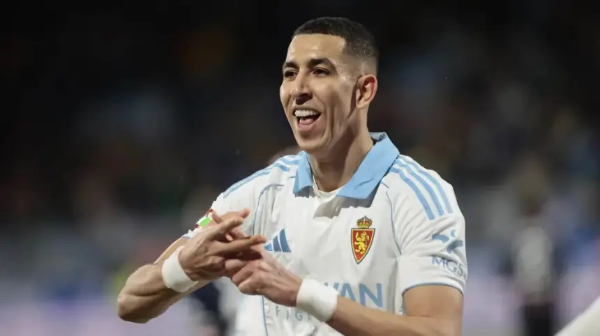 Marokkaanse voetballer Youssef En-Nesyri juicht na het scoren van een doelpunt, gekleed in het blauw-witte tenue van Real Zaragoza tijdens een wedstrijd.