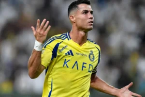 Ronaldo in a vibrant yellow Al Nassr kit, gesturing in frustration during a match, highlighting his intensity on the pitch.
