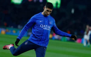 Achraf Hakimi in a blue PSG training kit, warming up on the pitch ahead of a match, showcasing his agility and focus.
