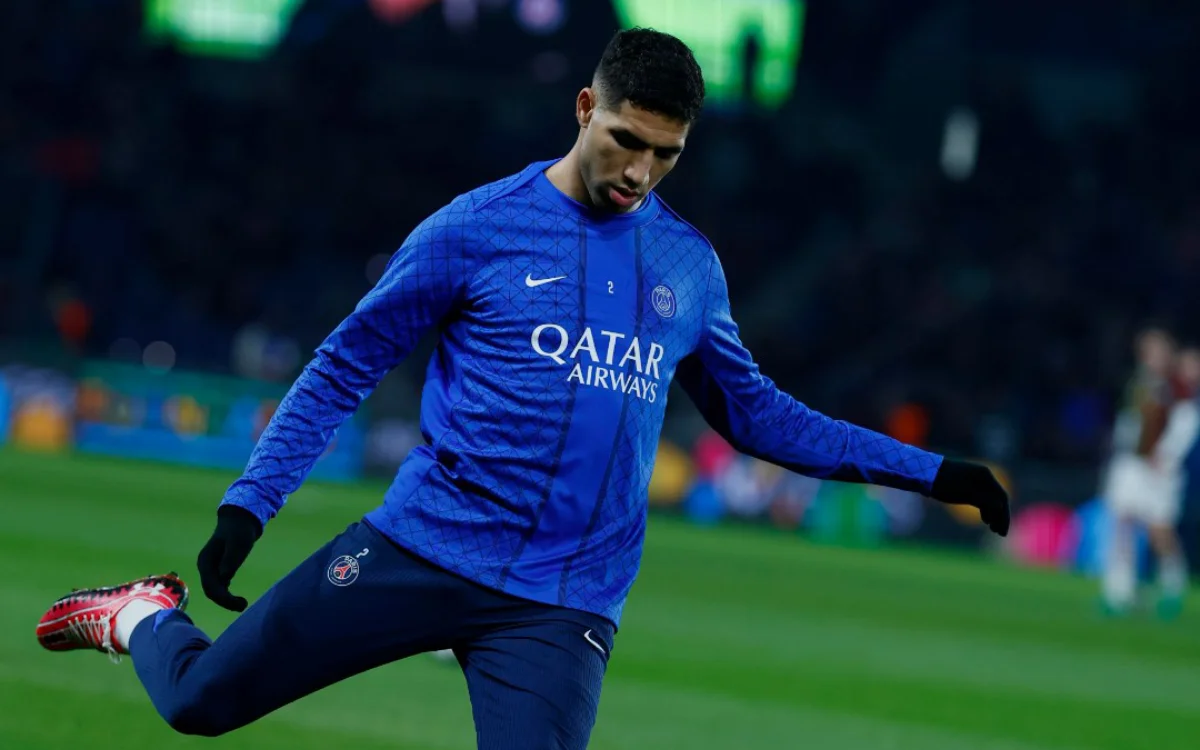 Achraf Hakimi in a blue PSG training kit, warming up on the pitch ahead of a match, showcasing his agility and focus.