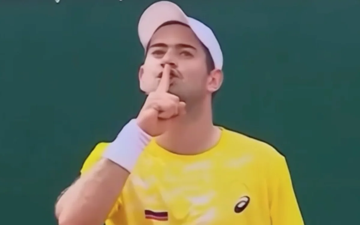 Moroccan tennis player celebrating in a yellow shirt, gesturing for silence during the Davis Cup match against Colombia.