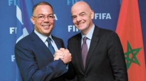 FIFA President Gianni Infantino shakes hands with Moroccan Football Federation President Fouzi Lekjaa, with Morocco's flag in the background.