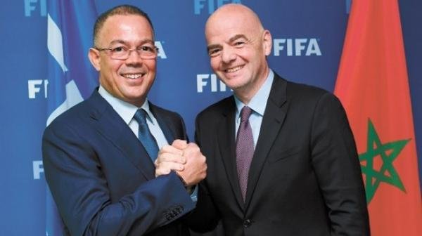 FIFA President Gianni Infantino shakes hands with Moroccan Football Federation President Fouzi Lekjaa, with Morocco's flag in the background.