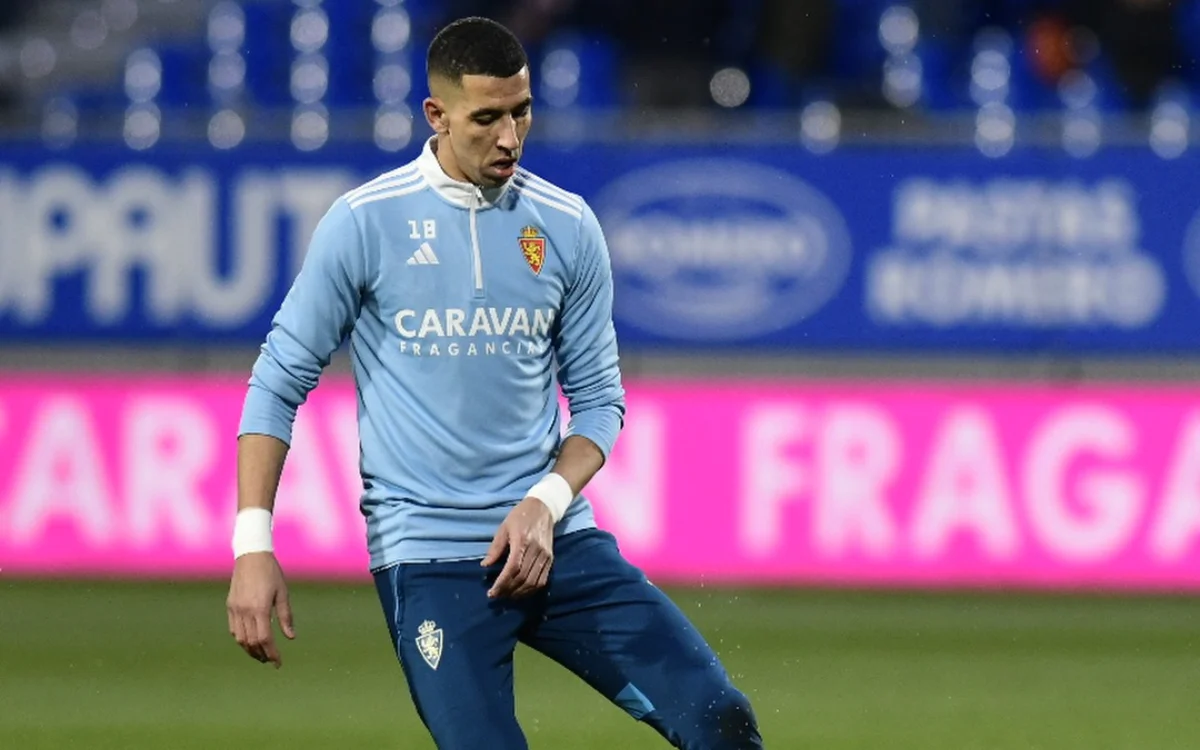 Jawad El Yamiq in a light blue Zaragoza training kit, focused during warm-up, with vibrant background lights at the stadium.