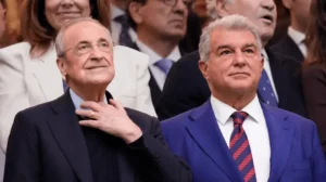 Florentino Pérez and Joan Laporta, club presidents, smiling at an event, surrounded by a crowd of spectators in formal attire.