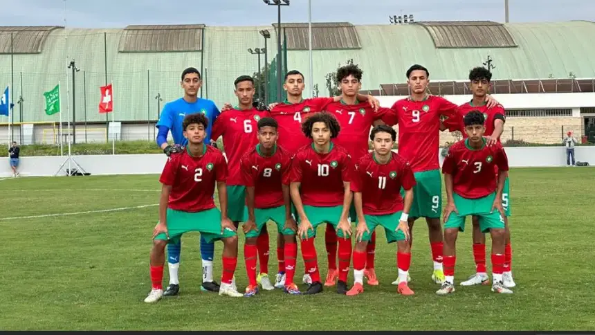 Morocco's U17 football team poses in red and green kits, ready for competition on a lush green pitch.