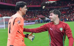 Marokkaanse spelers, doelman Yassine Bounou in oranje en speler Adam Masina in kastanjebruin, vieren op het veld na een wedstrijd.