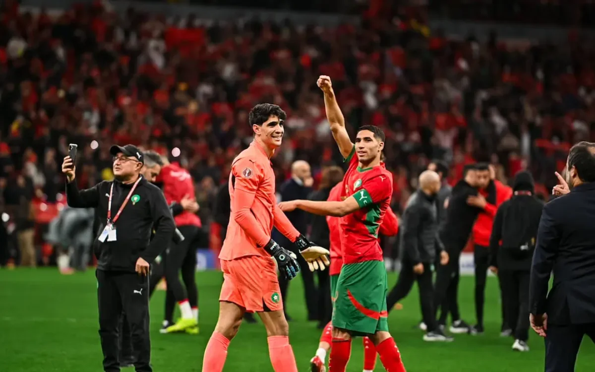 Marokko's doelman Yassine Bounou viert samen met Achraf Hakimi na een wedstrijd, met gepassioneerde fans op de achtergrond.
