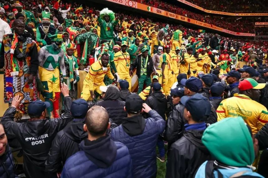 Energetic fans in yellow and green celebrate, adorned in traditional attire, during a vibrant football match, showcasing team spirit.