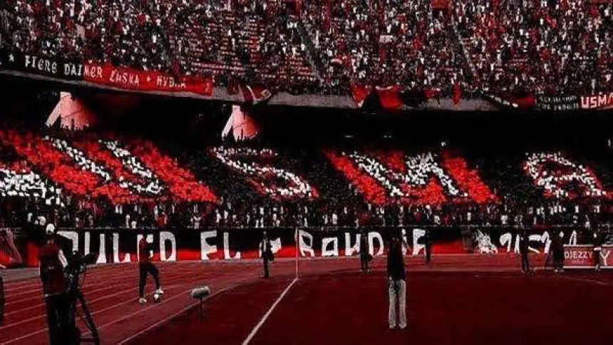 USMA fans displaying vibrant red and black colours in a vibrant stadium atmosphere, showcasing support for their team.