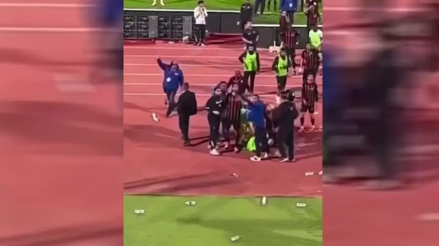 Players and staff from both teams engage in a heated confrontation on the pitch, surrounded by scattered cups and an animated crowd.